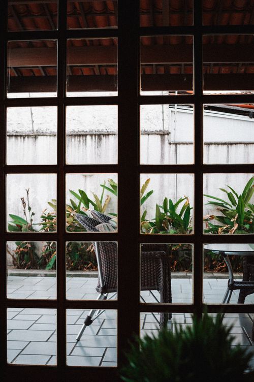 Free Peaceful patio view through window with chairs and tropical plants. Stock Photo