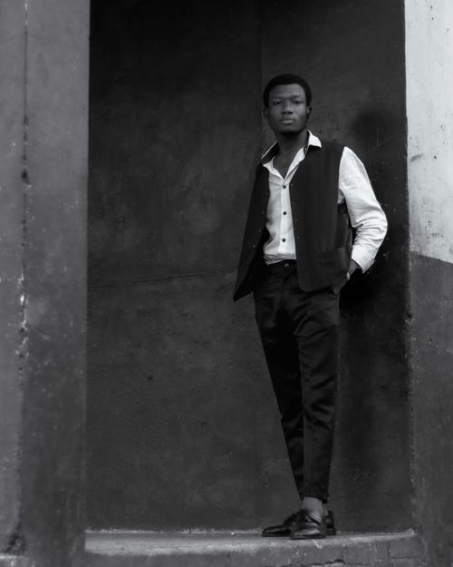 Free Monochrome portrait of a stylish young man leaning against a wall, exuding confidence. Stock Photo