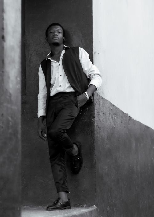 Free Artistic black and white portrait of a fashionable man leaning against a wall. Stock Photo