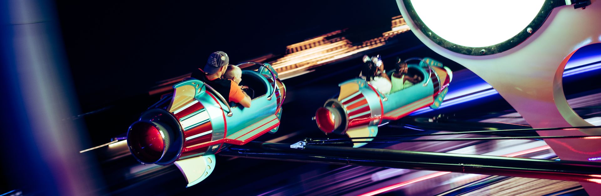 Exciting nighttime shot of futuristic amusement park ride with glowing elements and blurred motion.