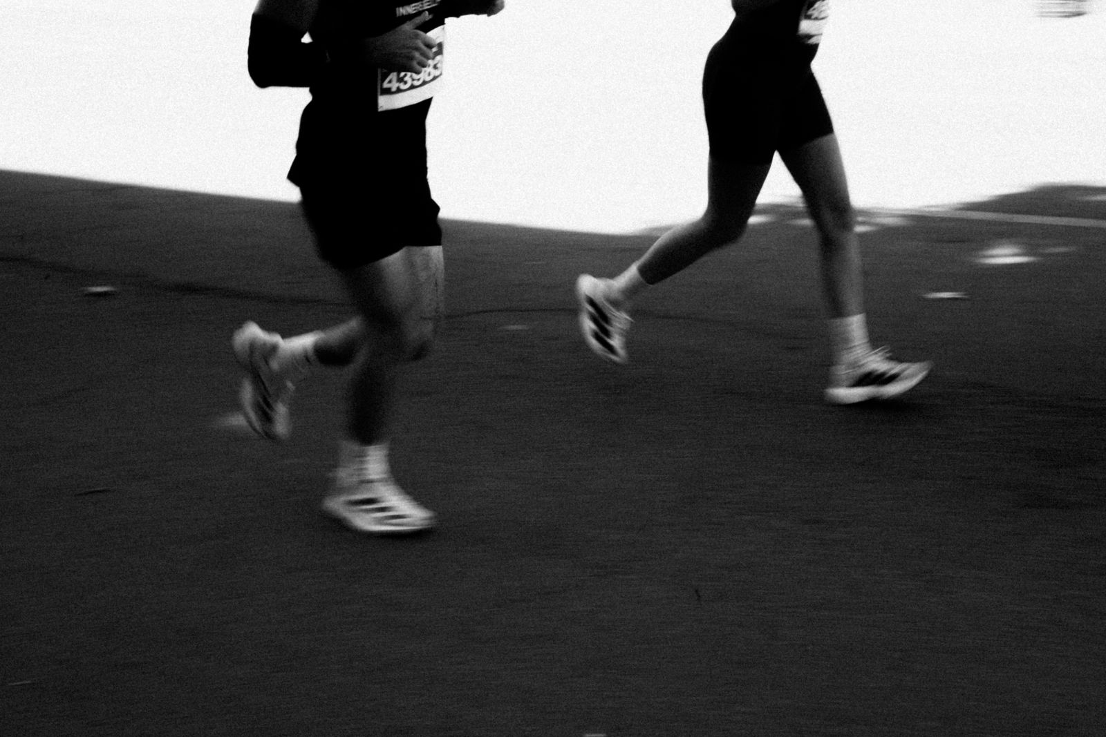 Runner on a bright outdoor road with knees in stride