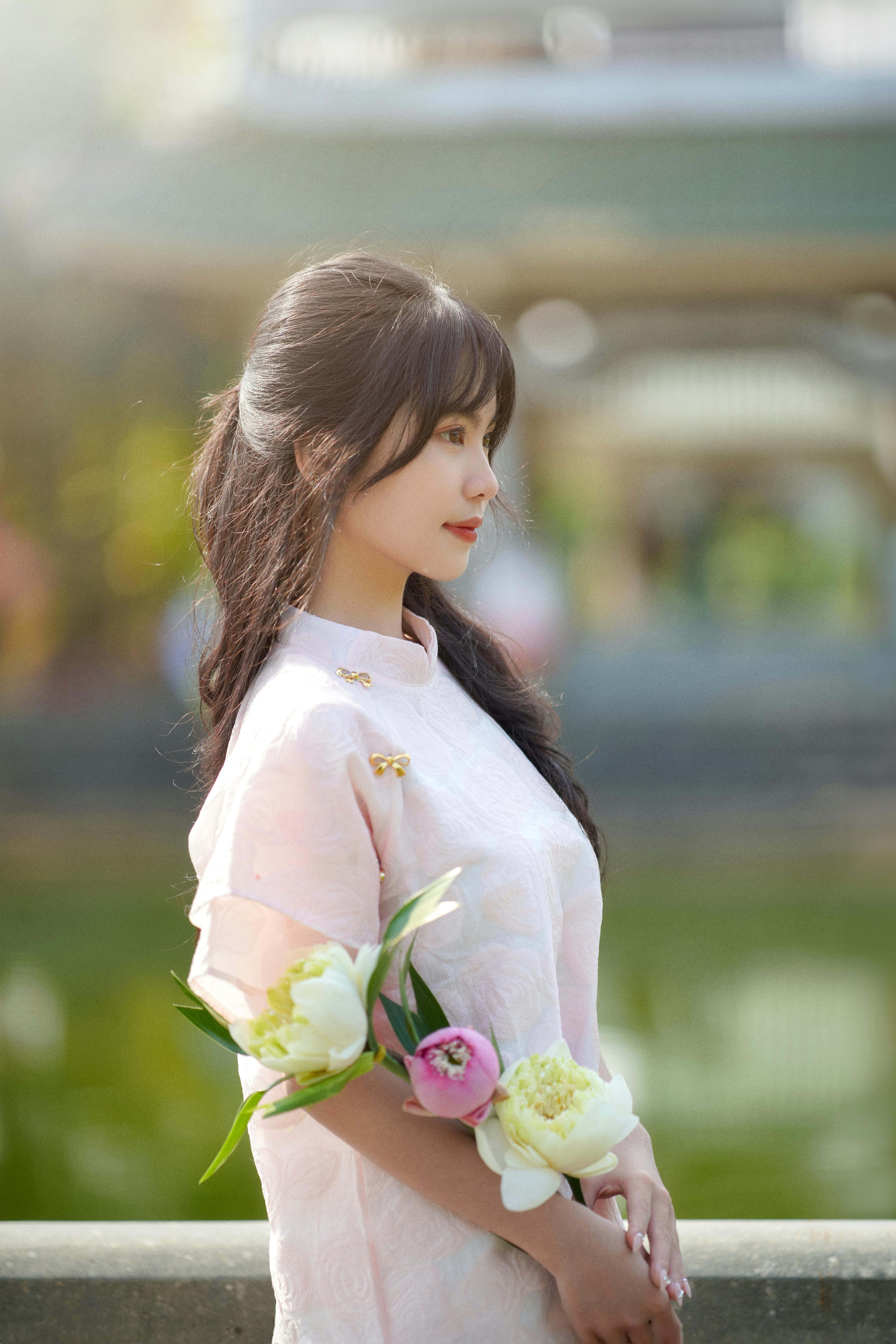 Profile of a woman in a pink dress holding peonies, symbolizing grace and beauty.