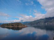 平静的湖泊倒映着群山环绕、云雾缭绕的岛屿田园风光