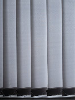 Close-up of modern vertical blinds in a contemporary office setting with natural light.