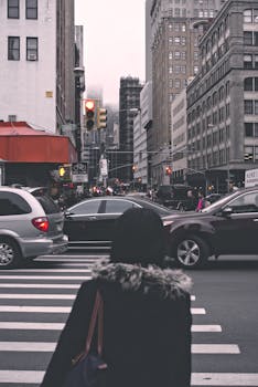 一个人穿过城市里一条繁忙的街道，周围车水马龙，高楼林立