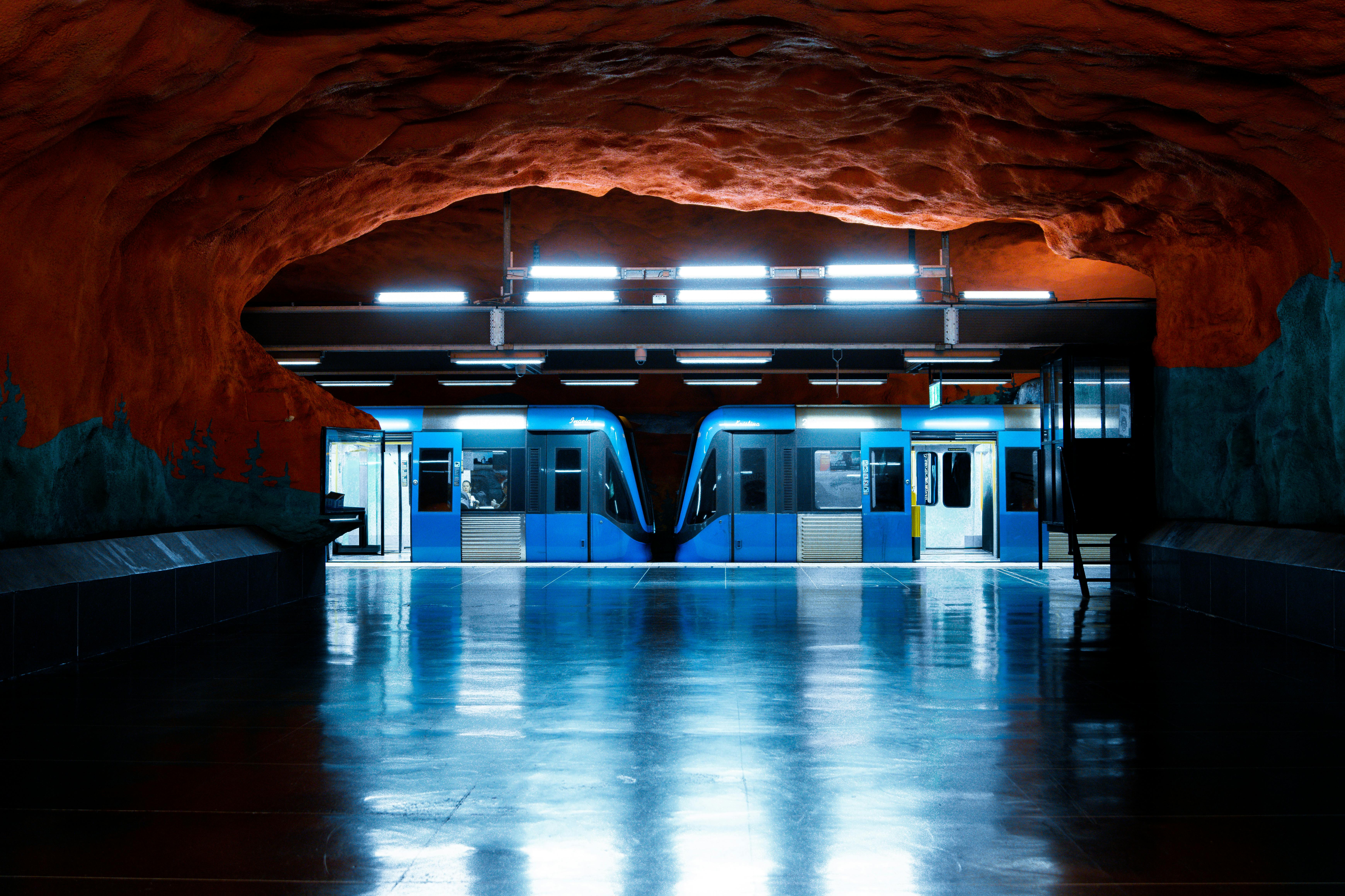 Elegant view of Stockholm metro station with distinctive cave-like walls and bright blue train.
