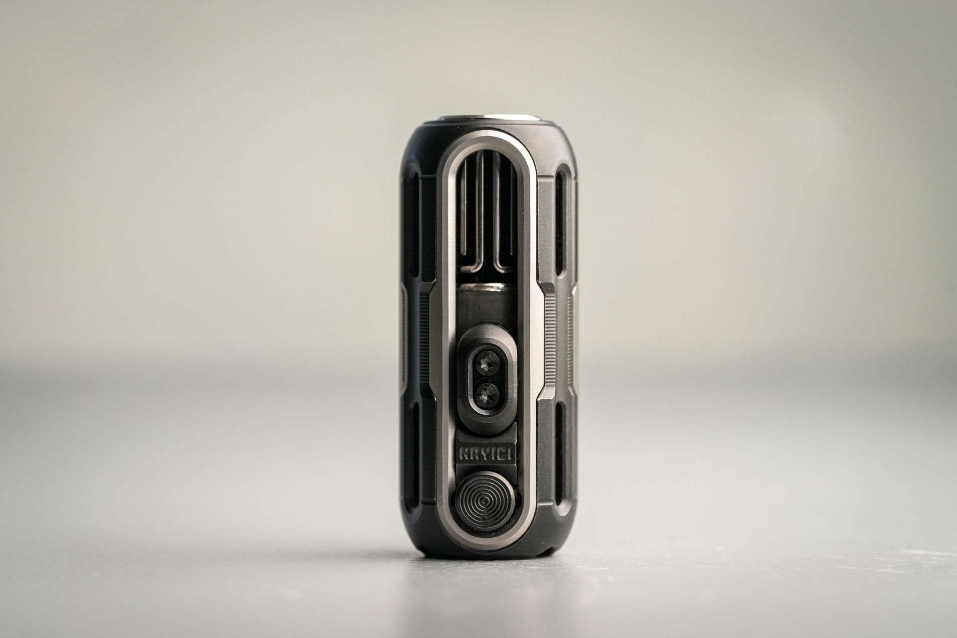 Sleek futuristic gadget with modern design standing vertically on a minimalist surface.