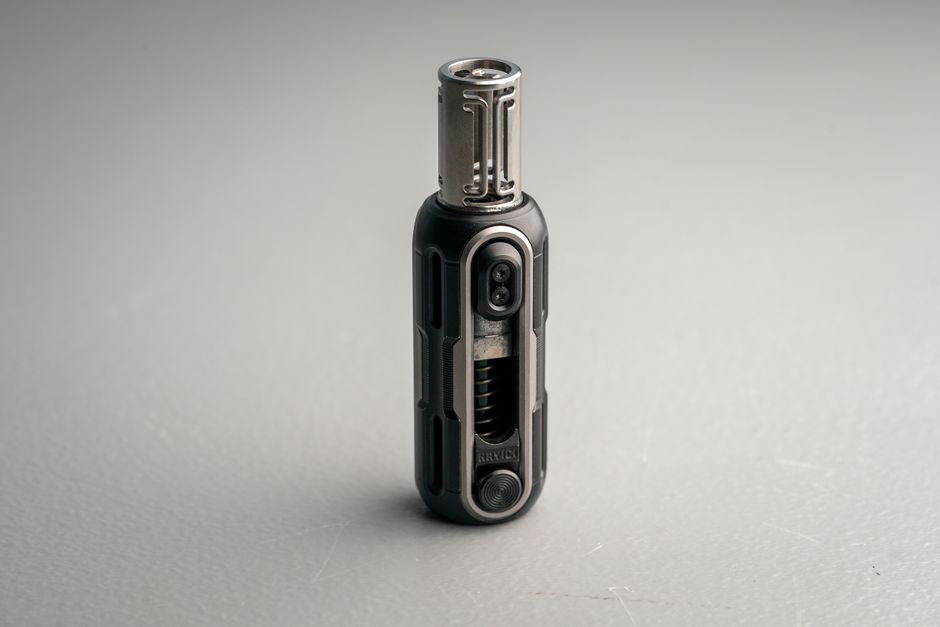 Close-up of a sleek, modern torch lighter with a metal design on a neutral gray background.