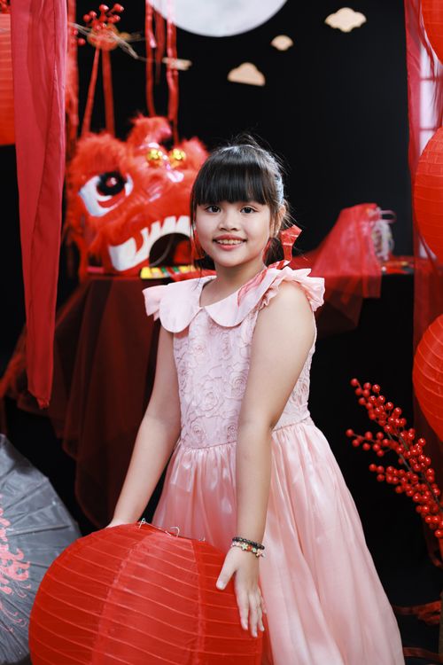 Free Young girl in pink dress with red lantern celebrating Lunar New Year indoors. Stock Photo