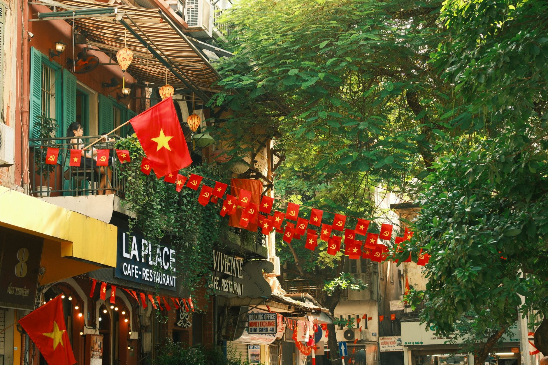 Colorful street in Vietnam adorned with vibrant flags and lush greenery.