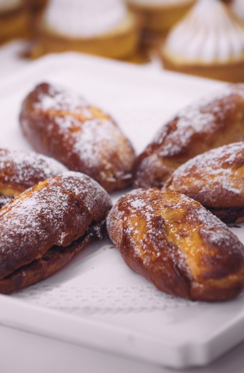 Free Close-up of freshly baked pastries dusted with powdered sugar on a tray in a kitchen setting. Stock Photo