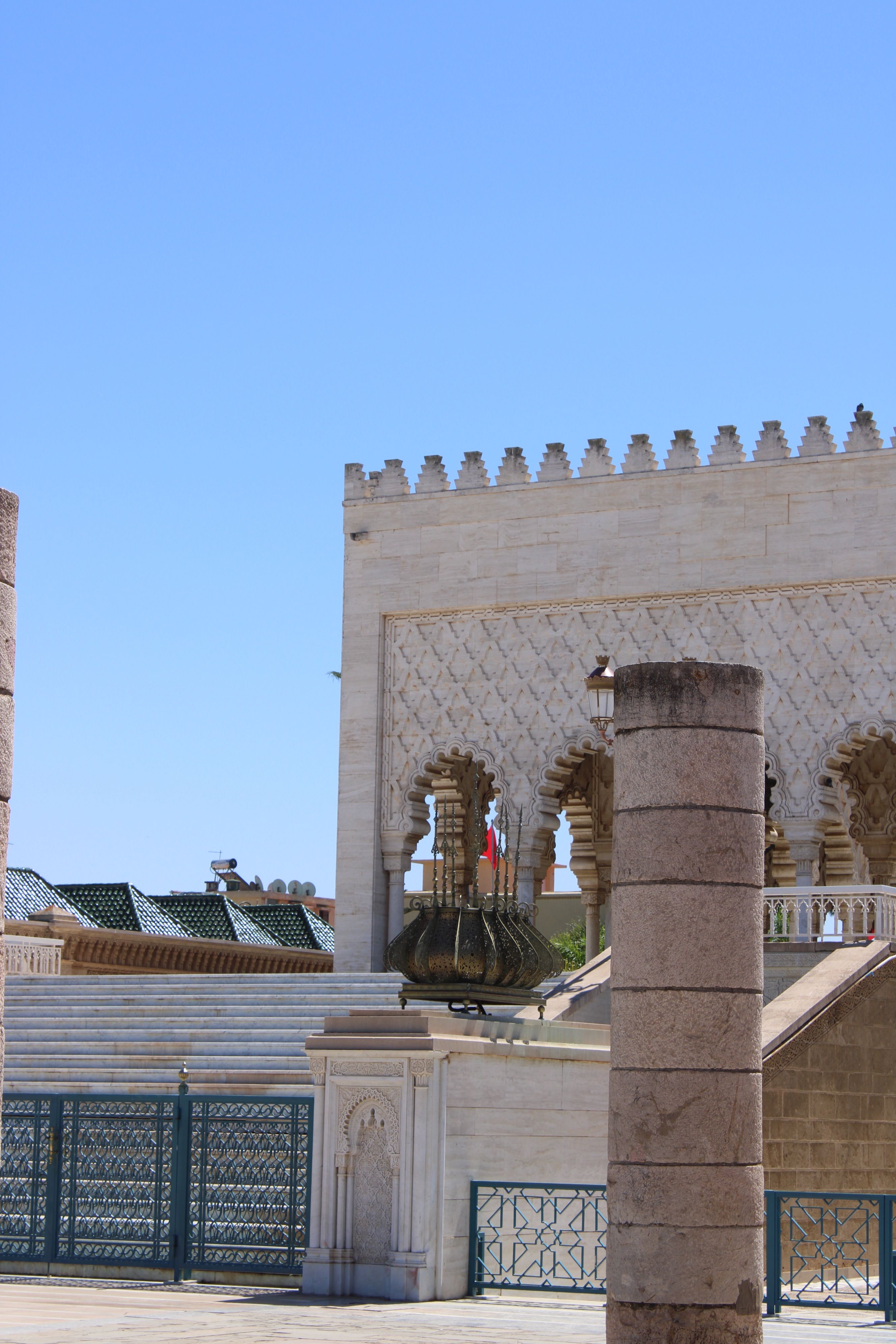 Stone columns and intricate architecture of a mausoleum against a clear blue sky in Rabat, Morocco.