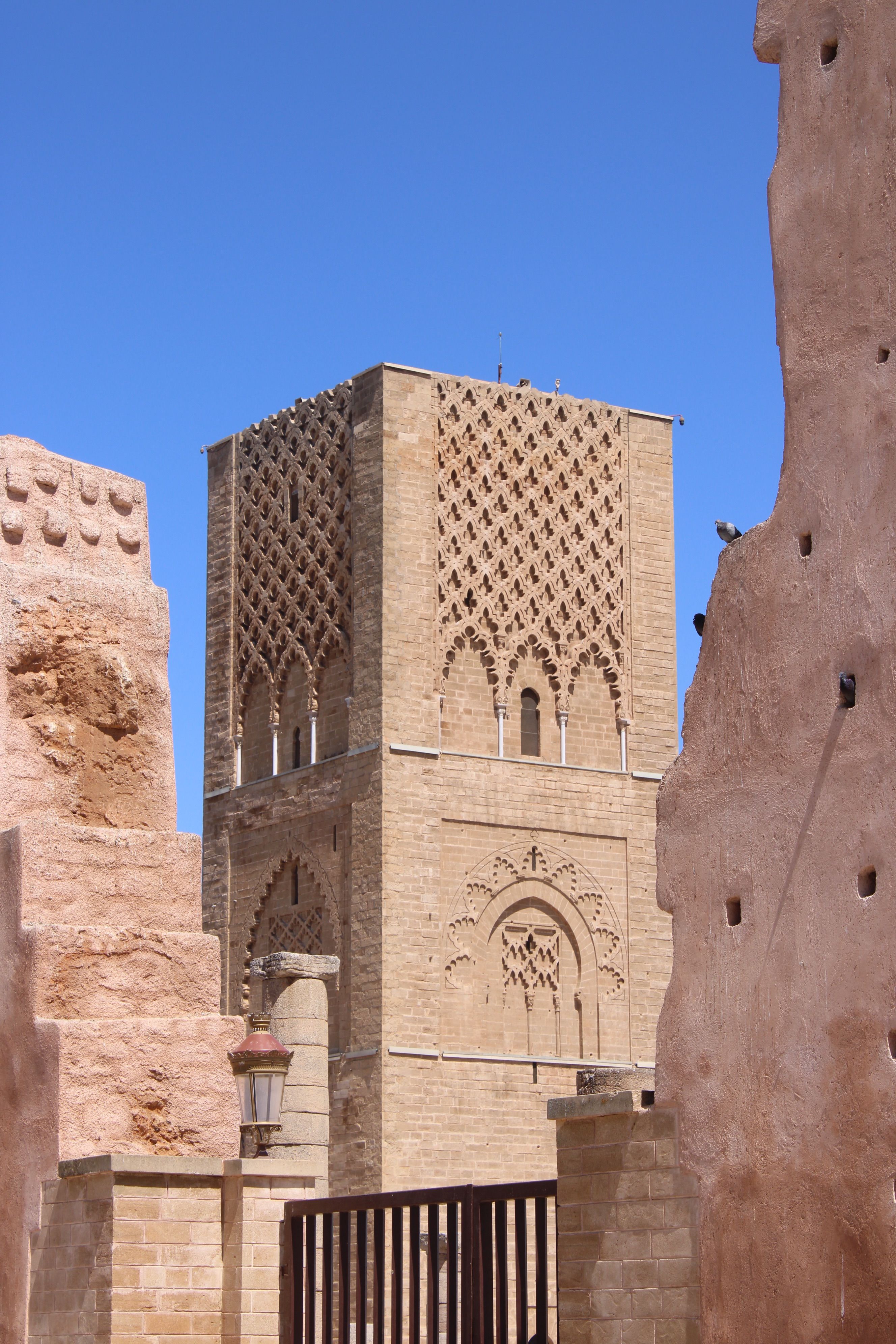 A view of the iconic Hassan Tower with intricate architecture in Rabat, Morocco under a blue sky.