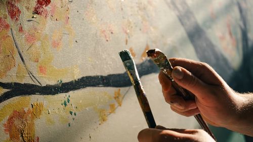 Free Close-up of hands painting abstract art on a canvas with brushes, highlighting creativity. Stock Photo