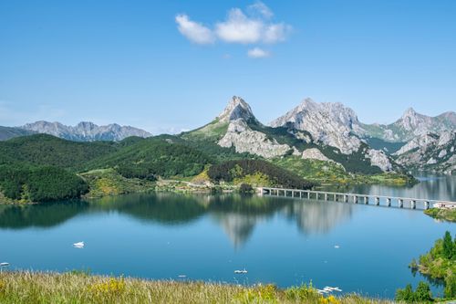 Free A serene landscape showcasing a mountain range reflected in a tranquil lake under a clear blue sky. Stock Photo