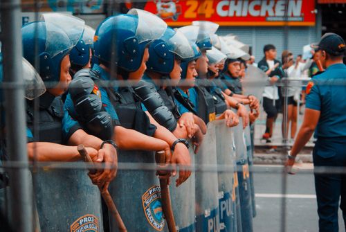 Free A line of police officers in riot gear standing on a street during a public gathering. Stock Photo