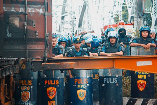 Free Police in riot gear stand behind shields during a protest in Manila, Philippines. Stock Photo