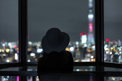 Free Silhouette of a woman looking at Tokyo city lights through a window at night. Stock Photo