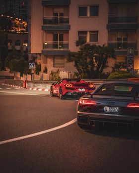 Night scene of luxury sports cars on a street corner in Monaco.