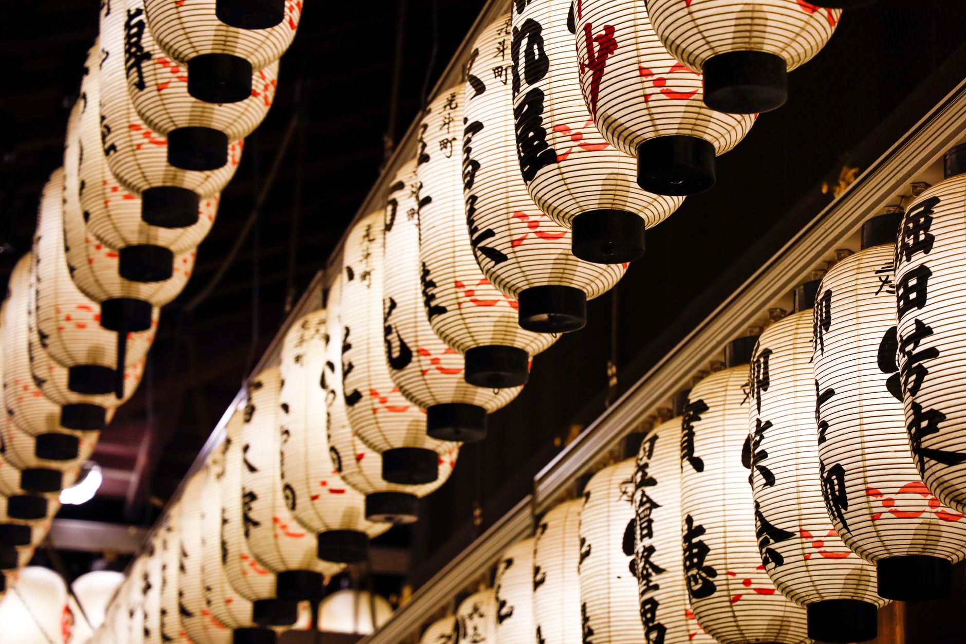 Rows of traditional Japanese lanterns with calligraphy, creating a warm, artistic atmosphere.