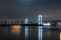 平静的河水倒映着东京彩虹桥和天际线明亮的夜间景观