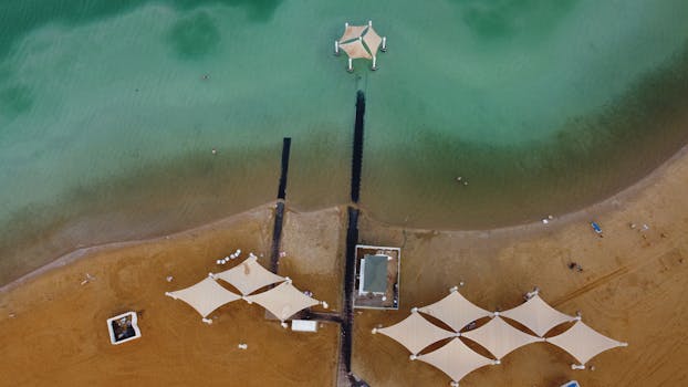 Aerial shot of a sandy beach with canopies and calm sea near the Dead Sea resort area.