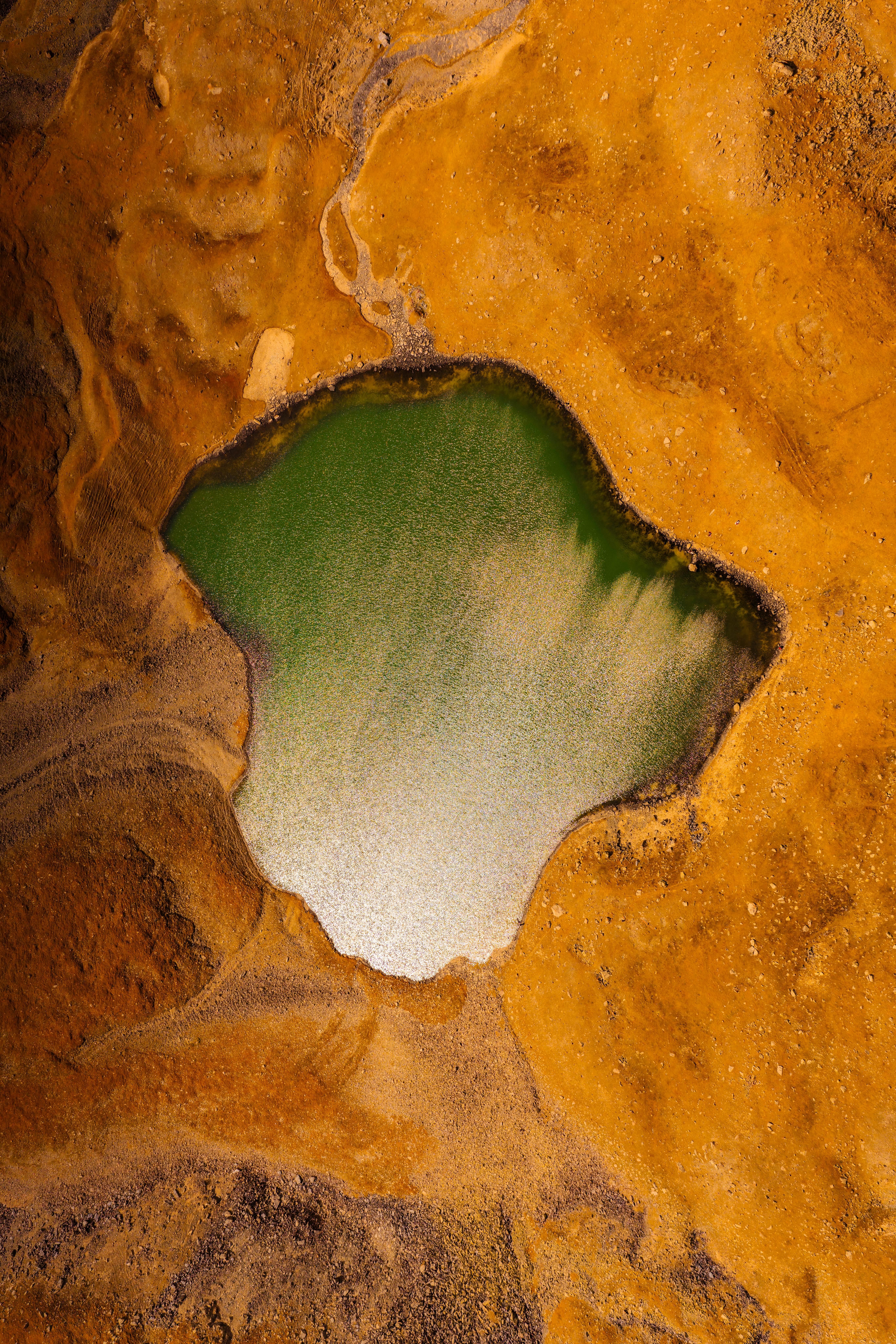 Stunning aerial shot of a green lake amid vivid desert terrain in Kyrgyzstan.