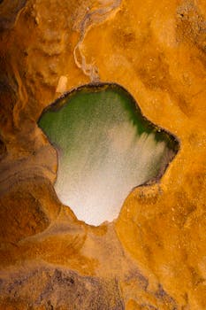 Stunning aerial shot of a green lake amid vivid desert terrain in Kyrgyzstan.