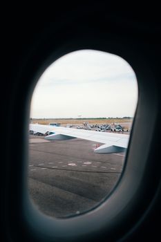 Captivating view of airplane wing from window seat, with runway and open sky in the background.
