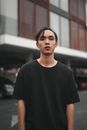 一名年轻人穿着休闲装，自信地站在城市的户外环境中