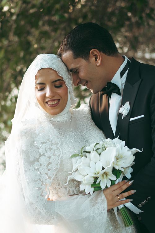 Free A joyful bride and groom share a tender moment in a lush outdoor setting. Stock Photo
