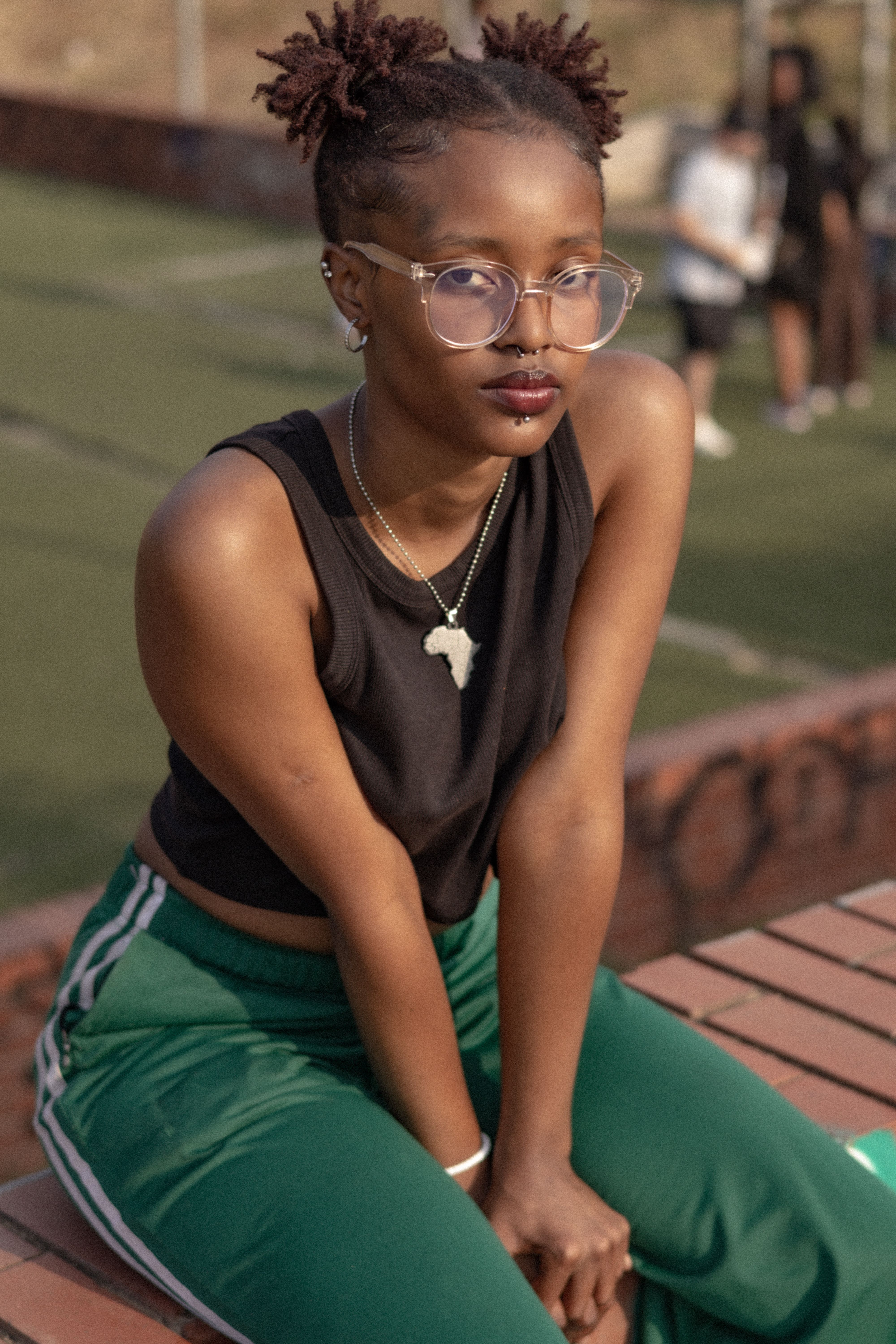 Young woman with glasses sitting outdoors in a casual outfit.