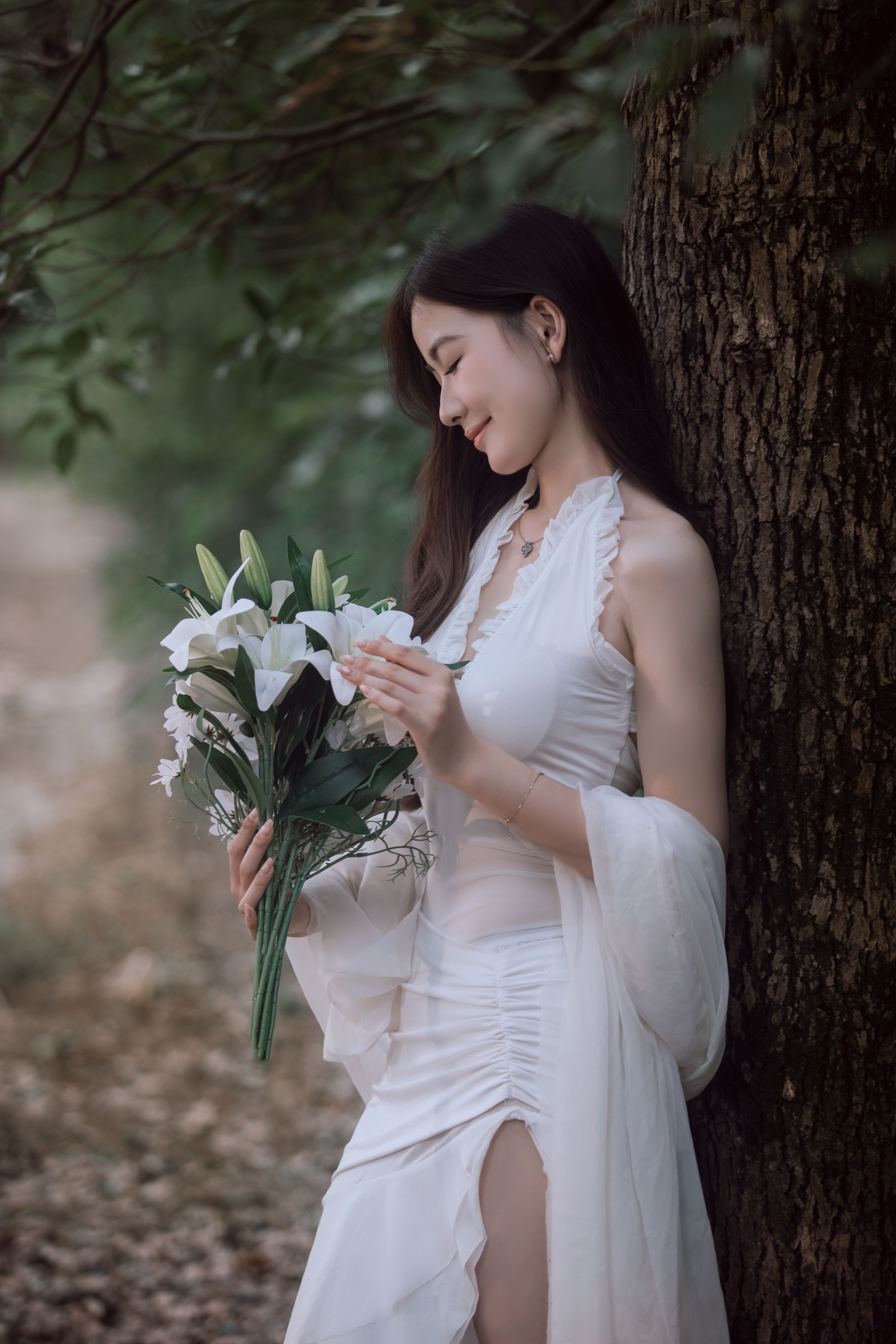 Elegant Woman in White Dress Holding Lilies Outdoors · Free Stock Photo