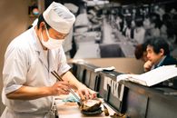 A sushi chef skillfully prepares seafood at a restaurant in Tokyo, showcasing Japanese culinary tradition.