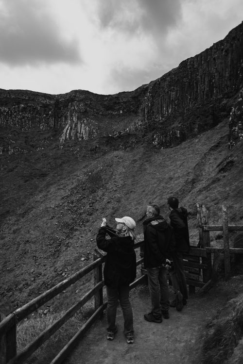 Free Three tourists admire the dramatic basalt cliffs in Northern Ireland, capturing nature's grandeur. Stock Photo
