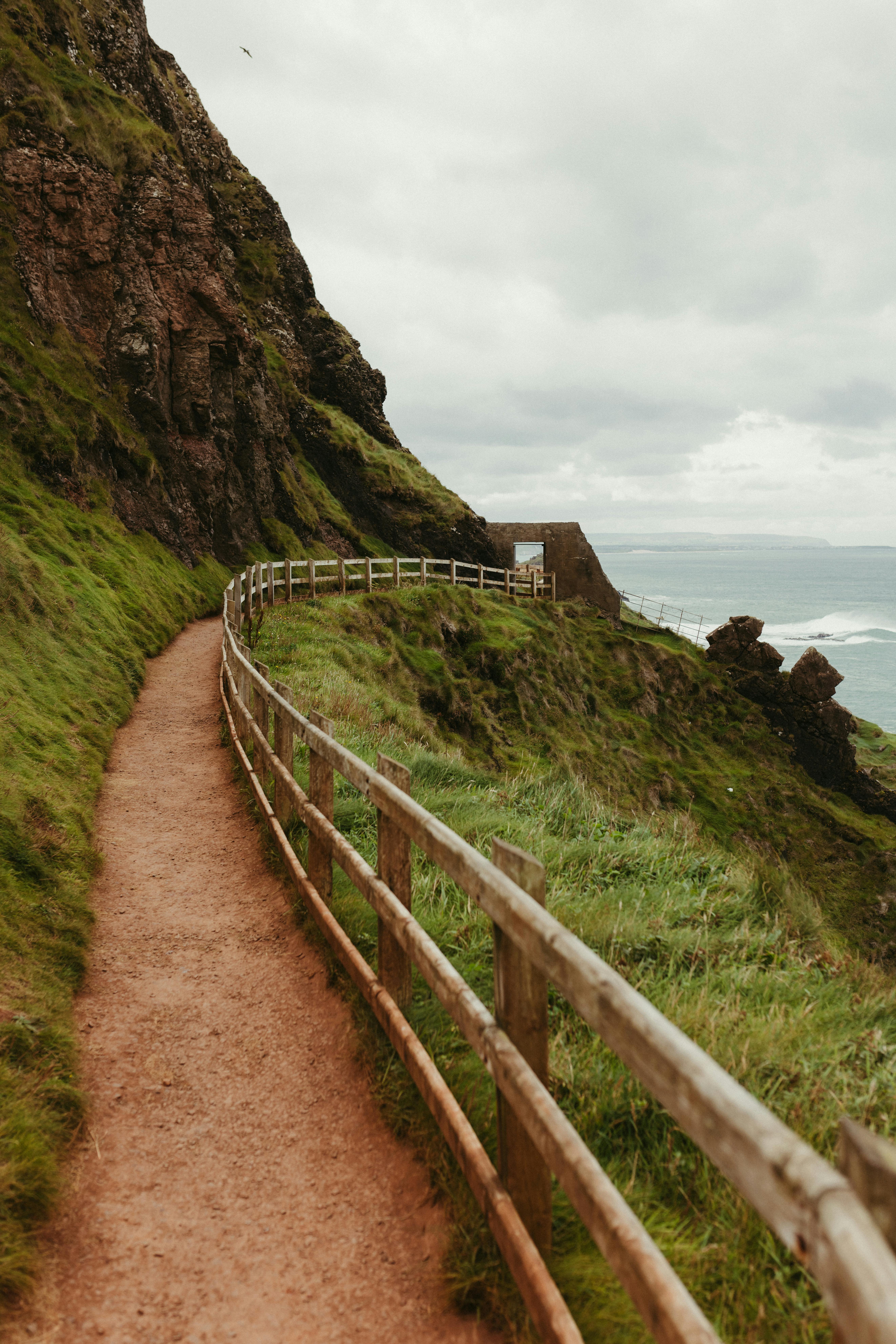 A picturesque coastal path along the cliffs of Northern Ireland, featuring lush greenery and ocean views.