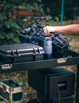 A detailed view of film equipment setup outdoors, featuring a camera, storage case, and other accessories.