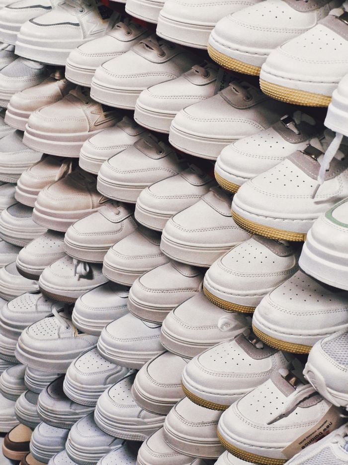 A large collection of white sneakers neatly arranged in a shoe store display. — photo by Dmitry Alexandrovich on Pexels