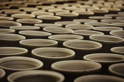 Multiple handcrafted clay pots aligned in a traditional pottery workshop.