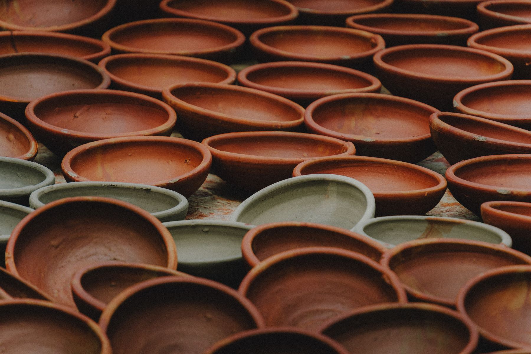 Rows of handmade terracotta and pale clay bowls on a shelf