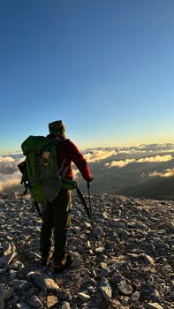 Lone hiker with backpack enjoys breathtaking mountain view at sunrise in Van, Türkiye.