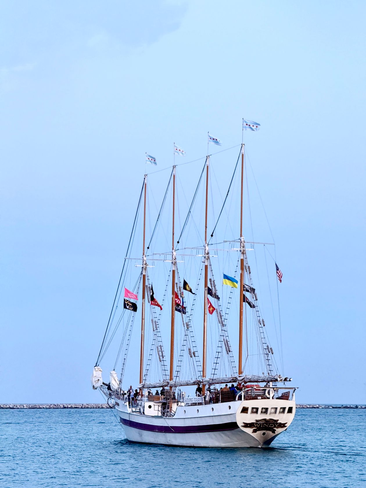 Majestic tall ship adorned with signal flags sailing on calm blue water at the Armada finale