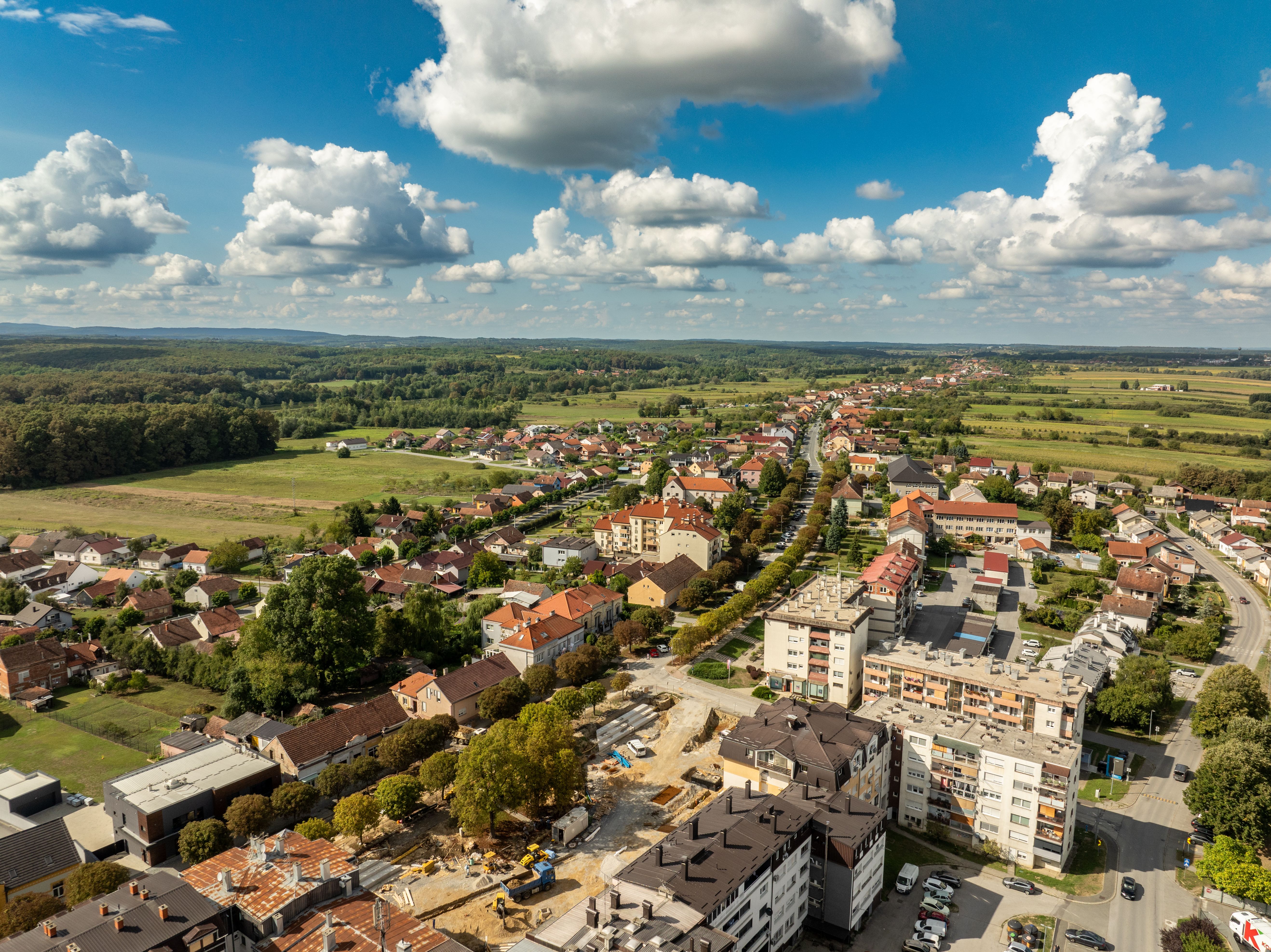 Aerial view of the rooftops and green fields in Garešnica, Croatia under a bright blue sky.