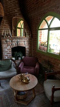 Warm, rustic indoor setting featuring brick fireplace, cozy chairs, and vintage decor.