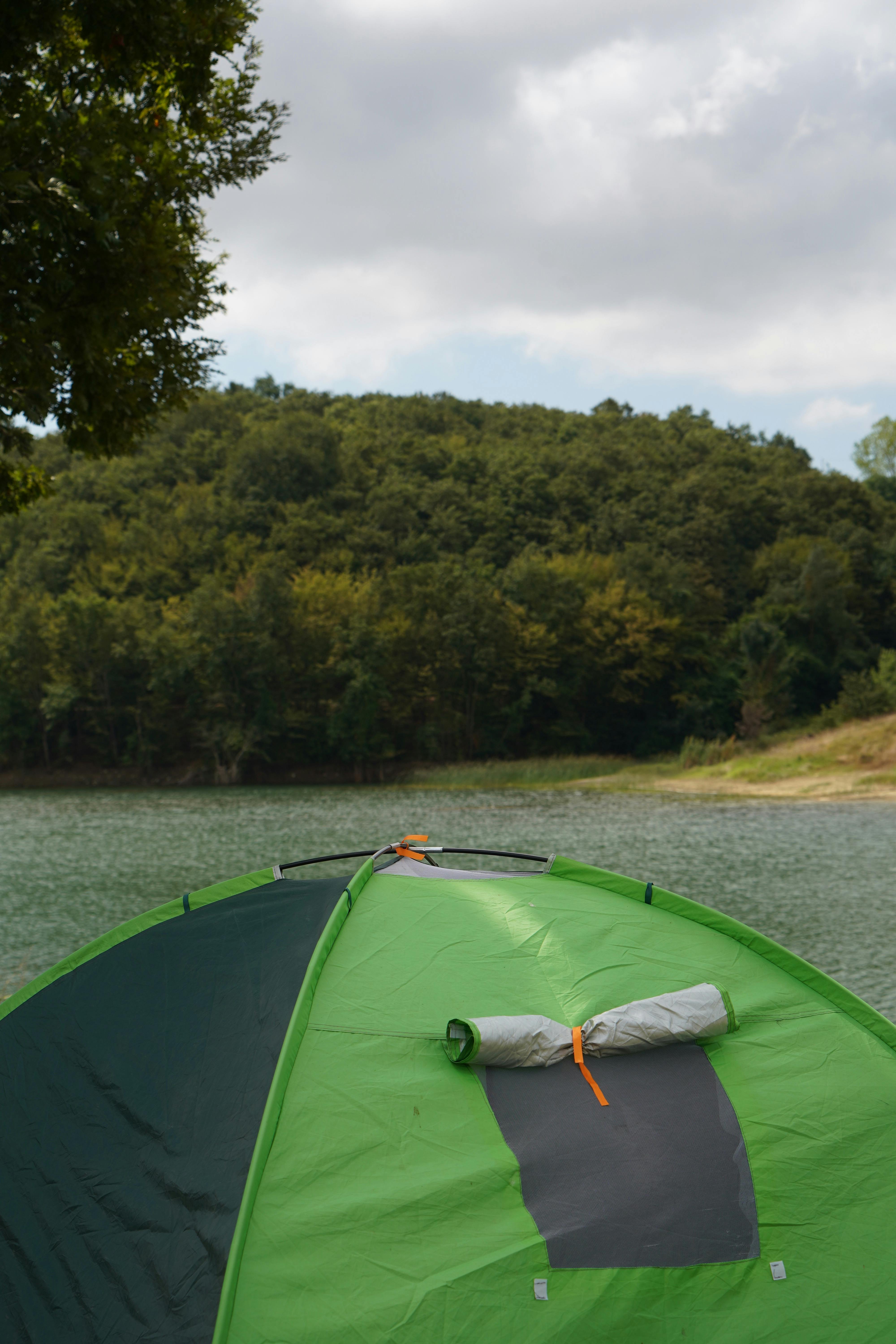 An RV parked at a wooded Indiana state park campground near a lake at sunrise