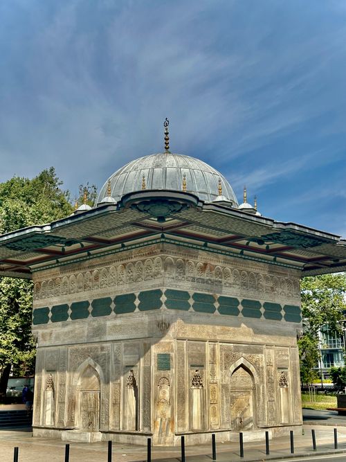 Free Ornate Ottoman-style fountain with dome in lush park setting, under sunny sky. Stock Photo