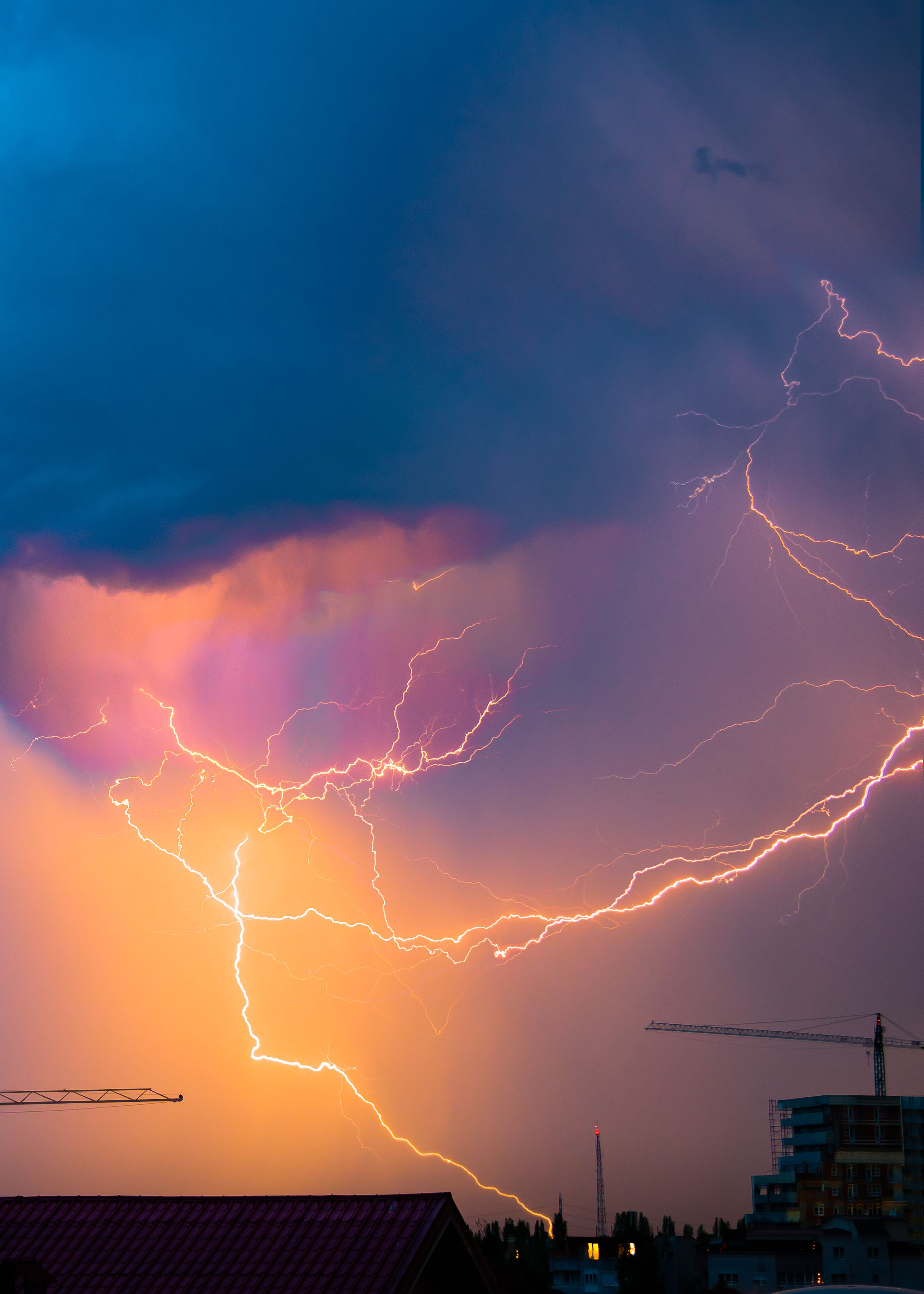 Dramatic lightning bolts illuminate the sky over an urban cityscape during a vibrant storm.