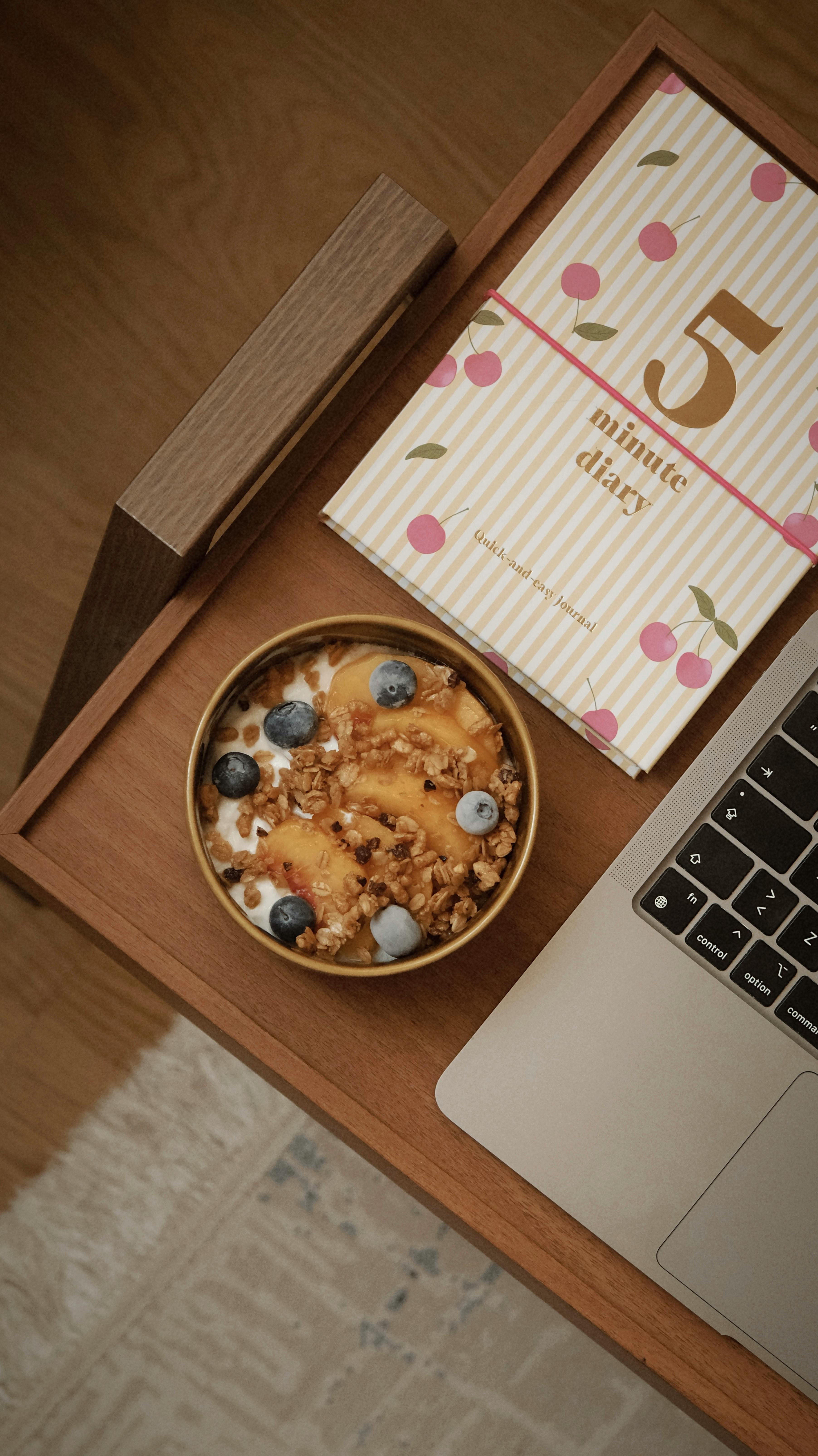 Modern flat lay of a healthy yogurt bowl with a notebook and laptop.