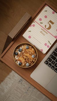 Modern flat lay of a healthy yogurt bowl with a notebook and laptop.