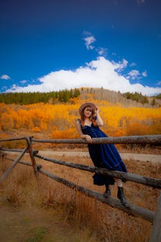 A woman in a blue dress poses against a vibrant fall backdrop in Breckenridge, Colorado.